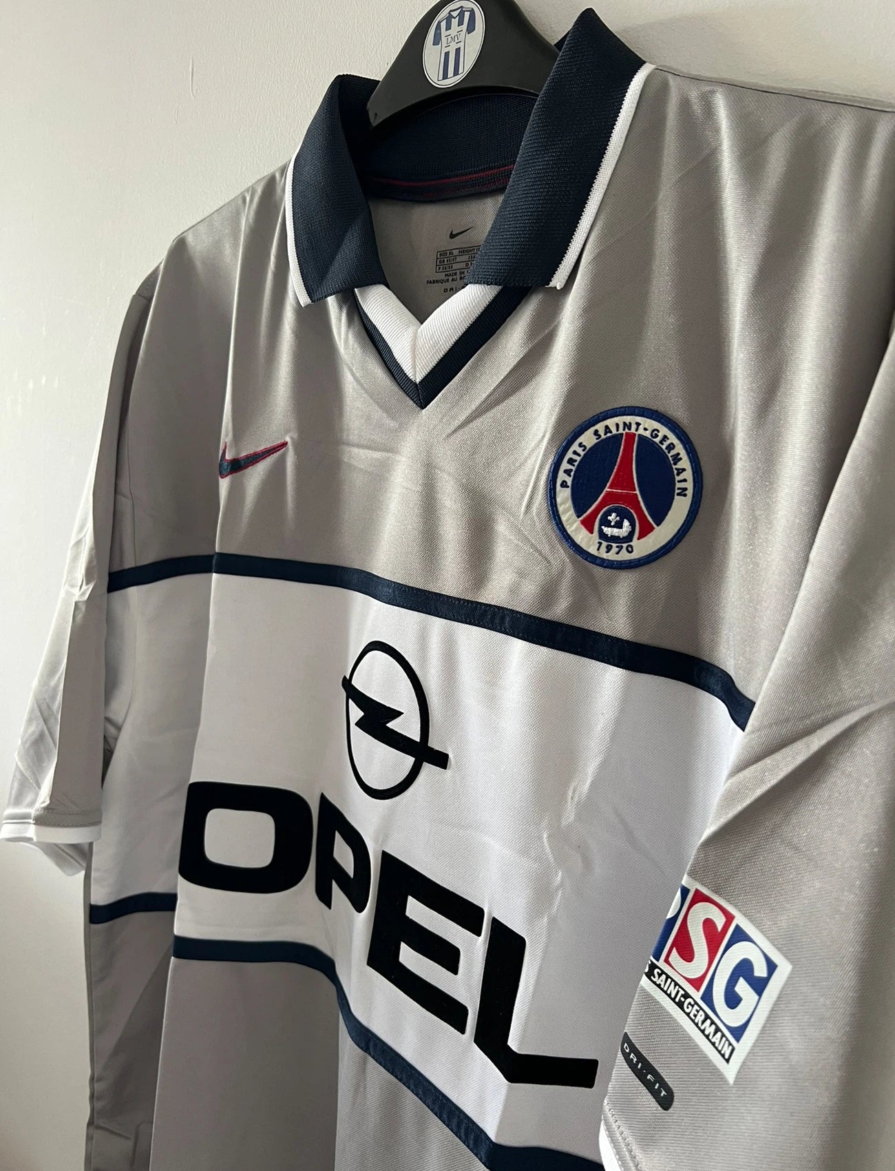 Maillot de foot vintage extérieur gris du PSG de la saison 2000/2001. On peut retrouver l'équipementier Nike et le sponsor Opel. Il s'agit d'un maillot authentique d'époque.