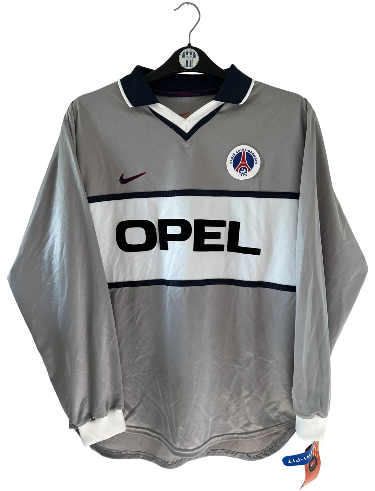 Maillot de foot vintage extérieur gris du PSG de la saison 2000/2001. On peut retrouver l'équipementier Nike et le sponsor Opel. Il s'agit d'un maillot authentique d'époque issu du stock pro du club.