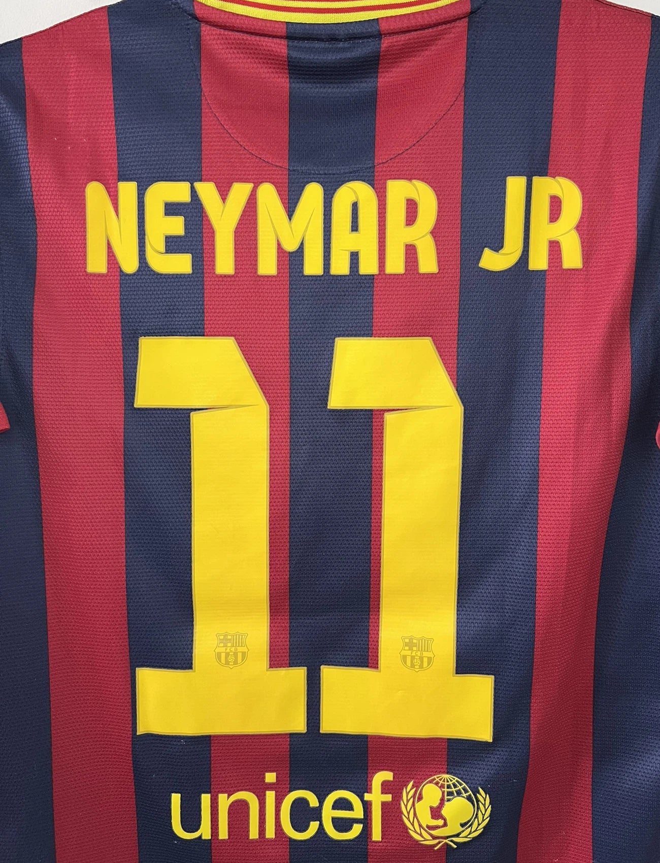 Maillot de foot vintage domicile du FC Barcelone de la saison 2013/14. Le maillot est de couleur rouge et bleu. On peut retrouver l'équipementier nike et le sponsor Qatar Airways. Le maillot est floqué du numéro 11 Neymar. Ils s'agit d'un maillot authentique comportant les numéros 532822-413