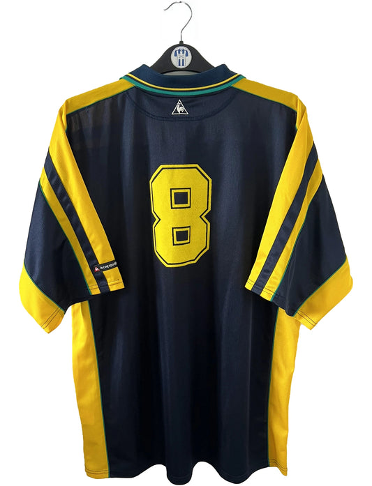 Maillot de foot vintage extérieur bleu et jaune du FC Nantes de la saison 2000-2001. On peut retrouver l'équipementier Le Coq Sportif et le sponsor Loxam. Le maillot est floqué du numéro 8 correspondant à Frédéric Da Rocha. Il s'agit d'un maillot authentique d'époque.