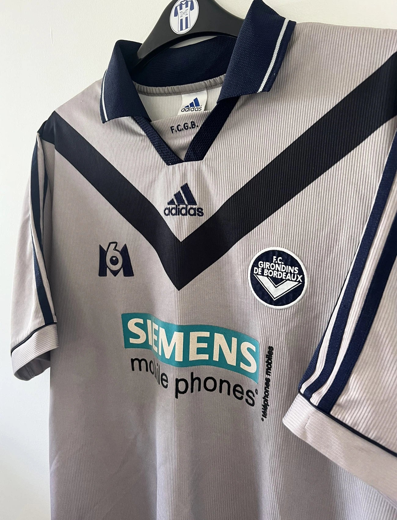 Maillot de foot vintage extérieur gris et bleu des girondins de bordeaux de la saison 2000/2001. On peut retrouver l'équipementier adidas et le sponsor Siemens et M6. Il s'agit d'un maillot authentique d'époque comportant l'étiquette 693826.