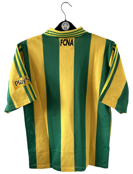 Maillot de foot vintage domicile jaune et vert du FC Nantes 1996/1997. On peut retrouver l'équipementier Adidas et le sponsor Eurest et Playstation. Il s'agit d'un maillot authentique d'époque.