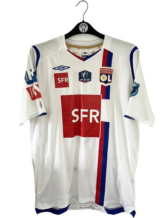 Maillot de foot vintage domicile blanc de l'OL de la saison 2007-2008. Il s'agit de l'édition coupe de france. On peut retrouver l'équipementier Umbro, ainsi que les sponsors SFR et Pitch. Le maillot est floqué du numéro 5 Mathieu Bodmer. Il s'agit d'un maillot authentique d'époque.