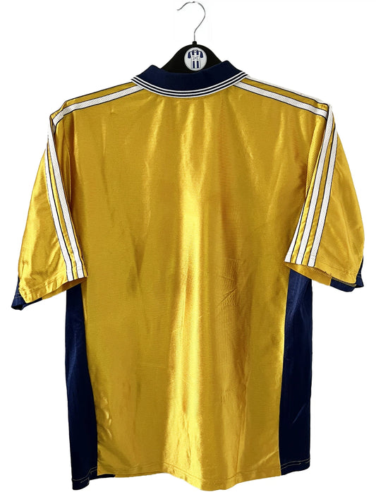 Maillot de foot vintage third de l'OM de la saison 1998-1999. Il s'agit du maillot édité pour le centenaire du club. Le maillot est de couleur dorée et bleu. On peut retrouver l'équipementier adidas et le sponsor ericsson. Il s'agit d'un maillot authentique d'époque.