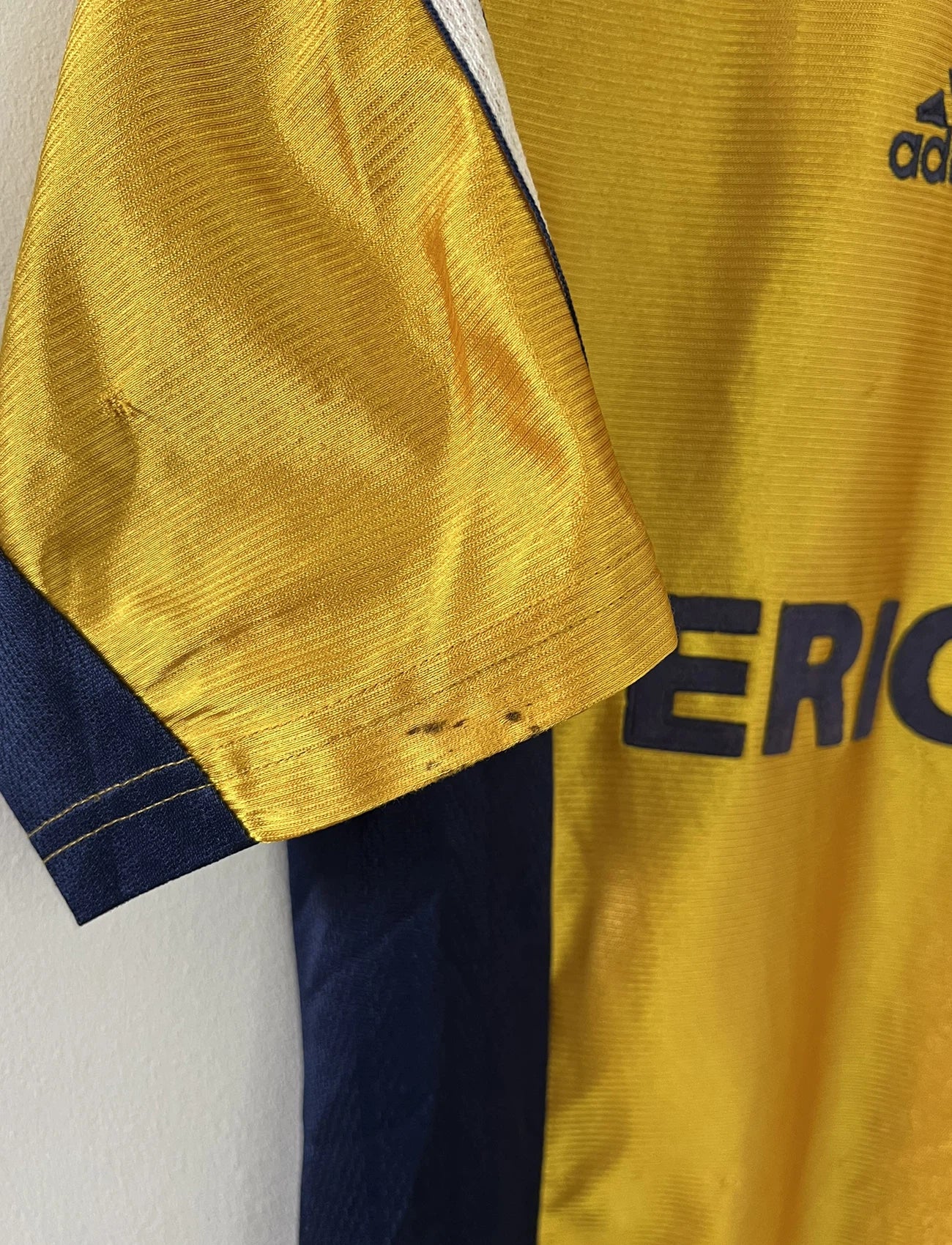 Maillot de foot vintage third de l'OM de la saison 1998-1999. Il s'agit du maillot édité pour le centenaire du club. Le maillot est de couleur dorée et bleu. On peut retrouver l'équipementier adidas et le sponsor ericsson. Il s'agit d'un maillot authentique d'époque.