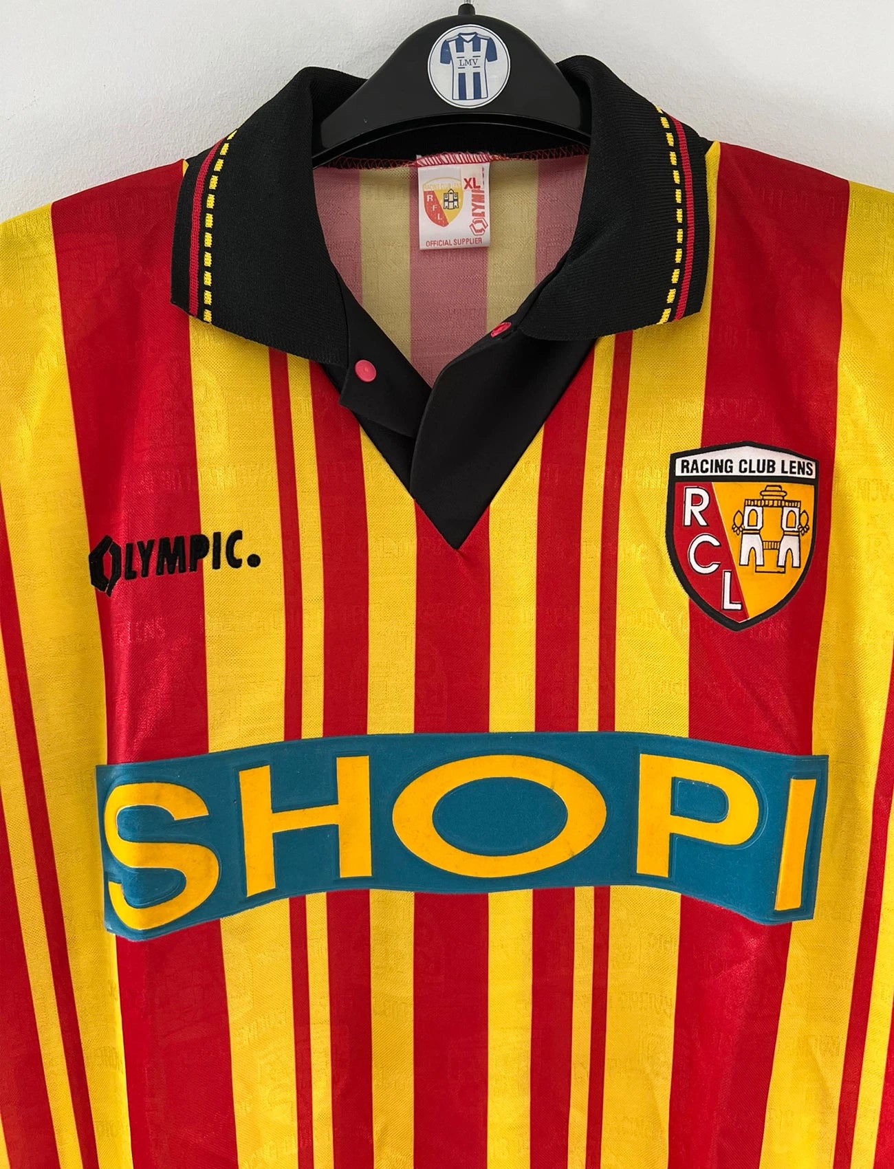 Maillot de foot vintage domicile rouge et jaune du RC Lens de la saison 1995/1996. On peut retrouver l'équipementier Olympic et le sponsor Shopi. Il s'agit d'un maillot authentique d'époque.