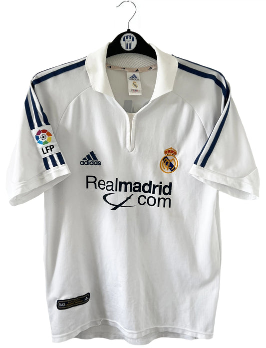 Maillot de foot vintage domicile du real madrid de la saison 2001-2002. Le maillot est de couleur blanc et noir. On peut retrouver l'équipementier adidas et le sponsor Real Madrid.com. Le maillot est floqué du numéro 5 Zinedine Zidane. Il s'agit d'un maillot authentique comportant les numéros 695856