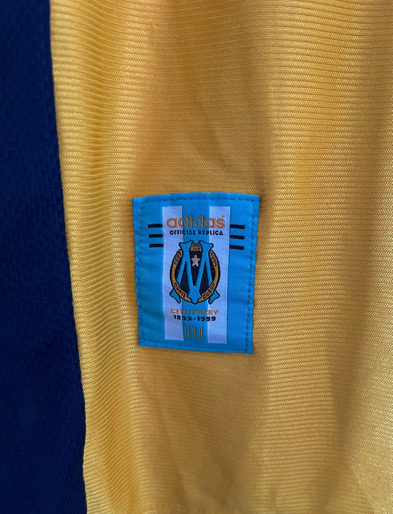 Maillot de foot vintage third doré de l'OM saison 1998/1999. On peut retrouver l'équipementier Adidas et le sponsor Ericsson. Il s'agit d'un maillot authentique d'époque.