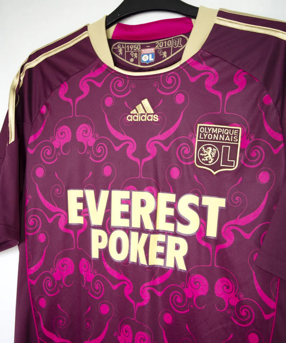 Maillot extérieur de l'ol de la saison 2010-2011. Le maillot est de couleur violet et dorée. On peut retrouver l'équipementier adidas et le sponsor everest poker
