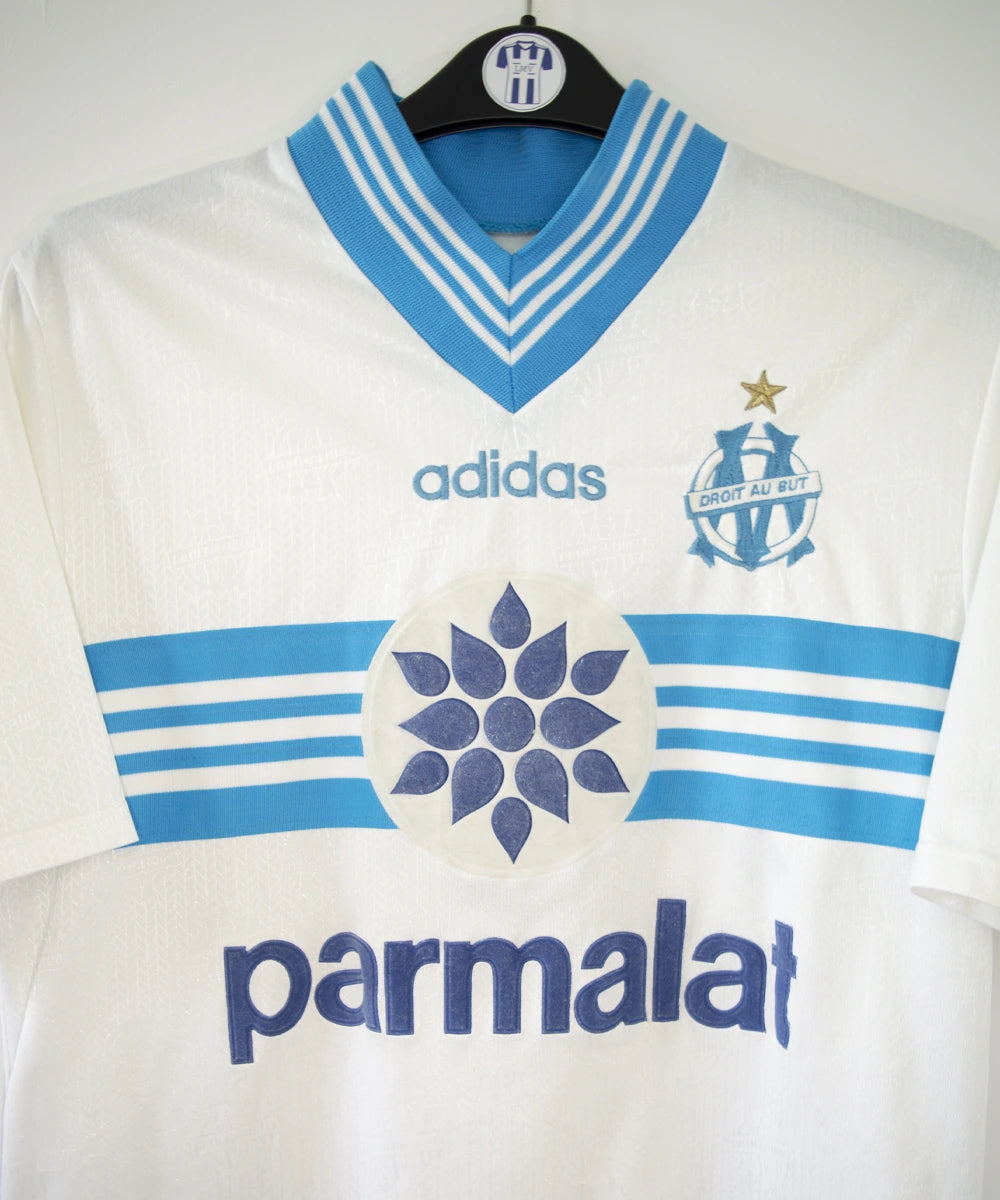 Maillot de foot vintage domicile blanc et bleu de l'om de la saison 1996/1997. On peut retrouver l'équipementier adidas et le sponsor Parmalat. Il s'agit d'un maillot authentique