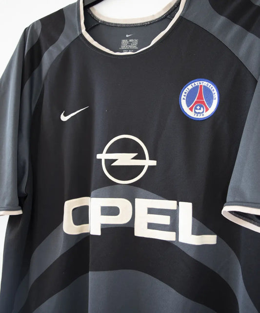 Maillot third du PSG de la saison 2001-2002. Le maillot est de couleur noir et gris. On peut retrouver le sponsor Opel ainsi que l'équipementier Nike.
