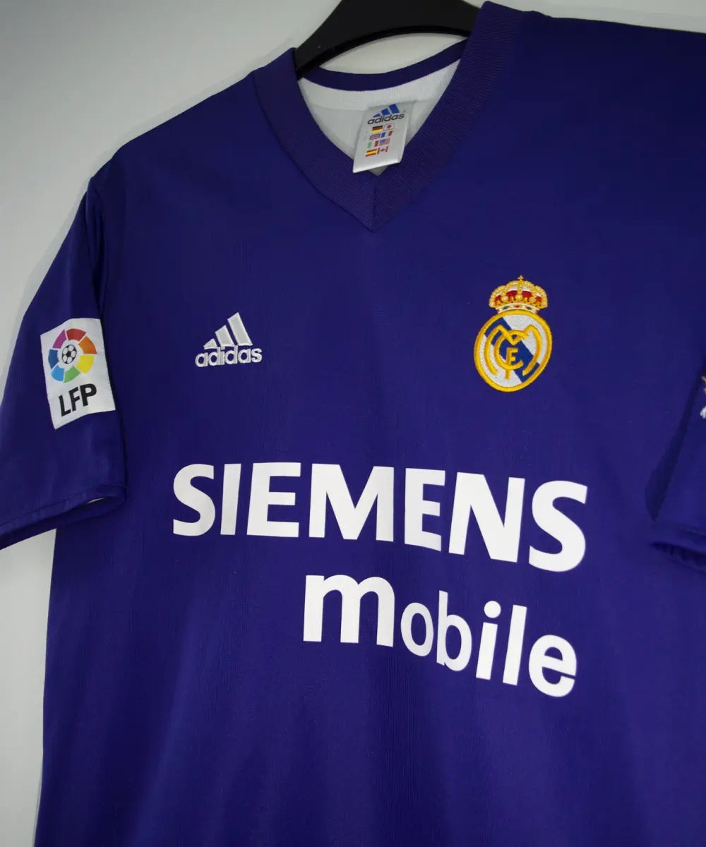 Maillot vintage violet et blanc third du real madrid de la saison 2002-2003. On peut retrouver l'équipementier adidas et le sponsor siemens mobile. Il s'agit du maillot du centenaire. Le maillot est floqué du numéro 5 Zinedine Zidane