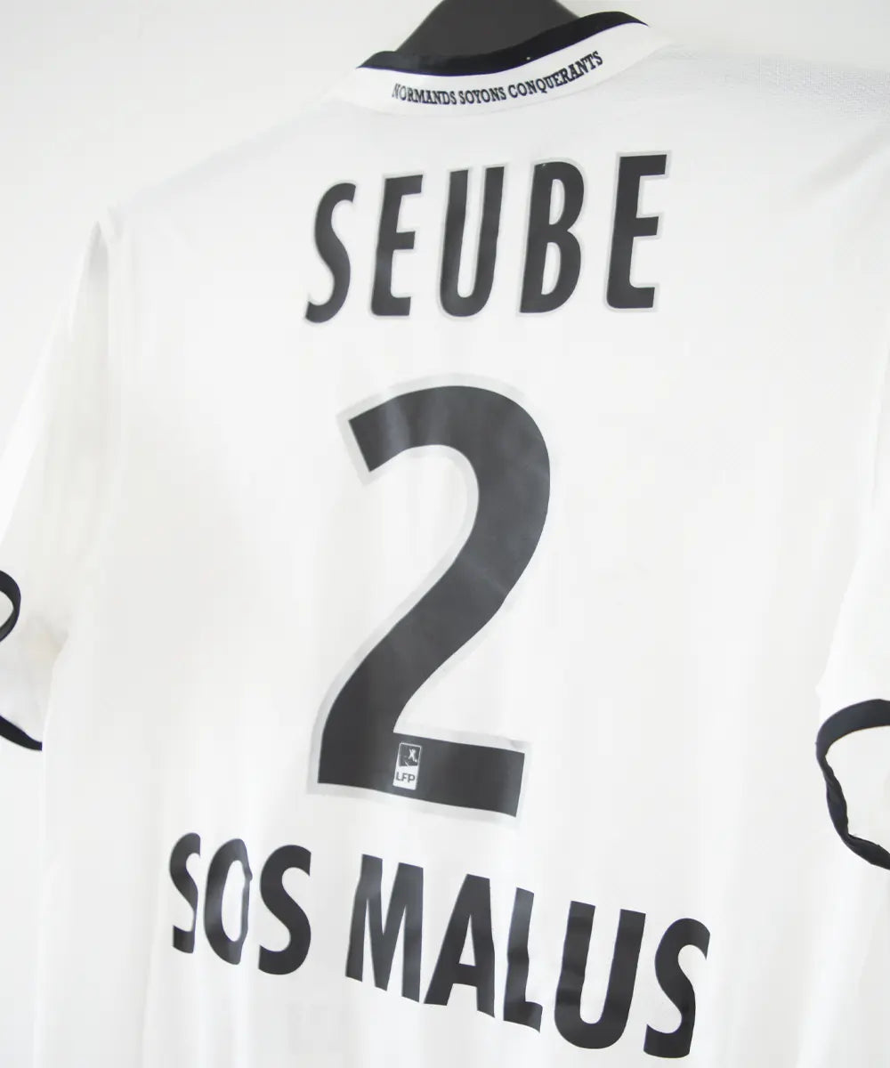 Maillot third du SM Caen de la saison 2014-2015 de couleur blanc et noir. On peut retrouver l'équipementier nike, le sponsor GDE et le sponsor SAS Malus. Le maillot est floqué du numéro 2 Nicolas Seube. Le maillot est aussi signé par Seube