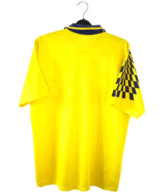 Maillot extérieur de Tottenham de la saison 1991-1995 de couleur jaune. On peut retrouver l'équipementier Umbro et le sponsor Holsten