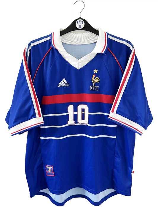 Maillot de foot vintage domicile de l'équipe de france 1998. On peut retrouver l'équipementier adidas. Le maillot est de couleur bleu blanc et rouge. Le maillot est floqué du numéro 10 Zinedine Zidane. Il s'agit d'un maillot authentique d'époque.