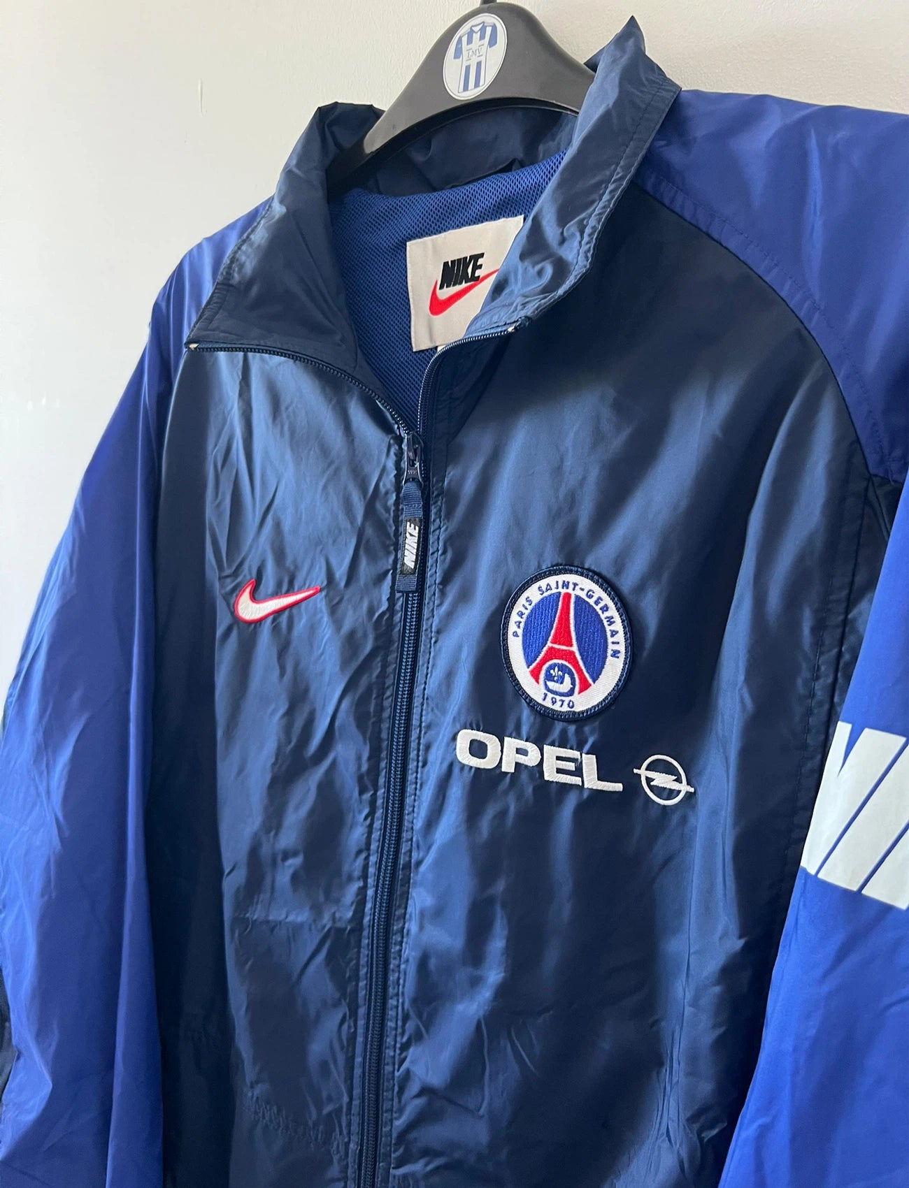 Veste bleue du PSG de la saison 1998/1999. On peut retrouver l'équipementier Nike et le sponsor Opel. Il s'agit d'une veste authentique d'époque.