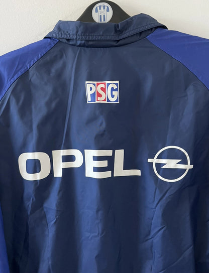Veste bleue du PSG de la saison 1998/1999. On peut retrouver l'équipementier Nike et le sponsor Opel. Il s'agit d'une veste authentique d'époque.