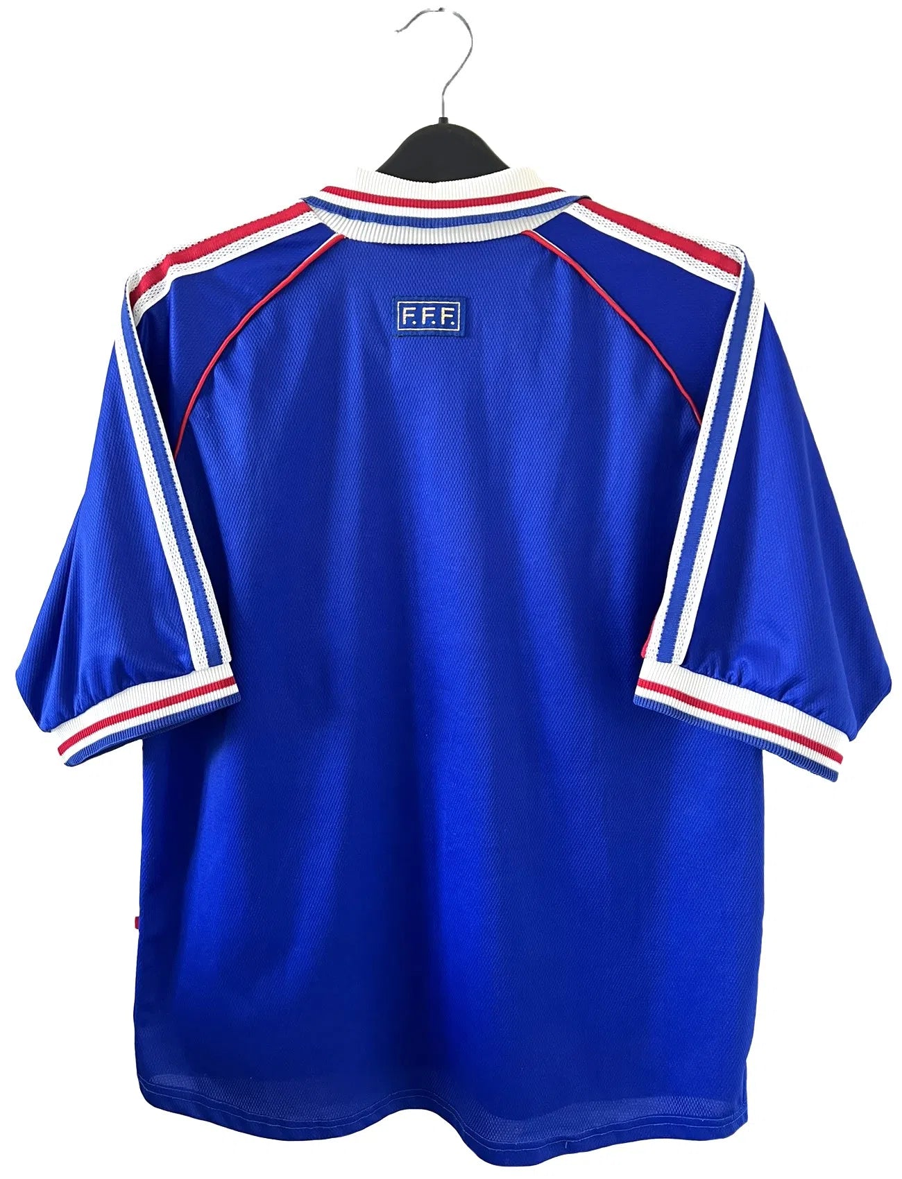 Maillot de foot vintage bleu blanc et rouge domicile de l'équipe de France 1998. On peut retrouver le sponsor adidas. On peut voir le coq sans l'étoile avec la signature "pour toi" de Zinedine Zidane. Il s'agit d'un maillot authentique.