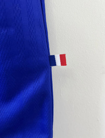 Maillot de foot vintage de l'équipe de france 98 bleu blanc et rouge. On peut retrouver l'équipementier adidas et le coq avec l'étoile. Il s'agit d'un maillot authentique édité lors de la coupe du monde 1998.