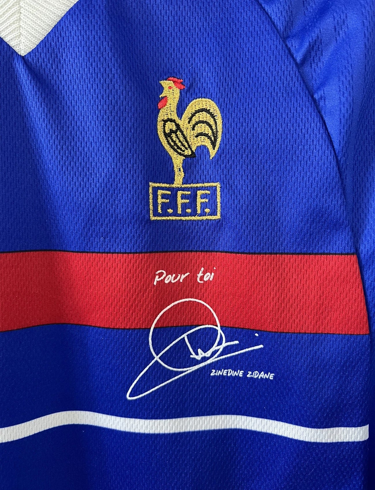 Maillot de foot vintage bleu blanc et rouge domicile de l'équipe de France 1998. On peut retrouver le sponsor adidas. On peut voir le coq sans l'étoile avec la signature "pour toi" de Zinedine Zidane. Il s'agit d'un maillot authentique.
