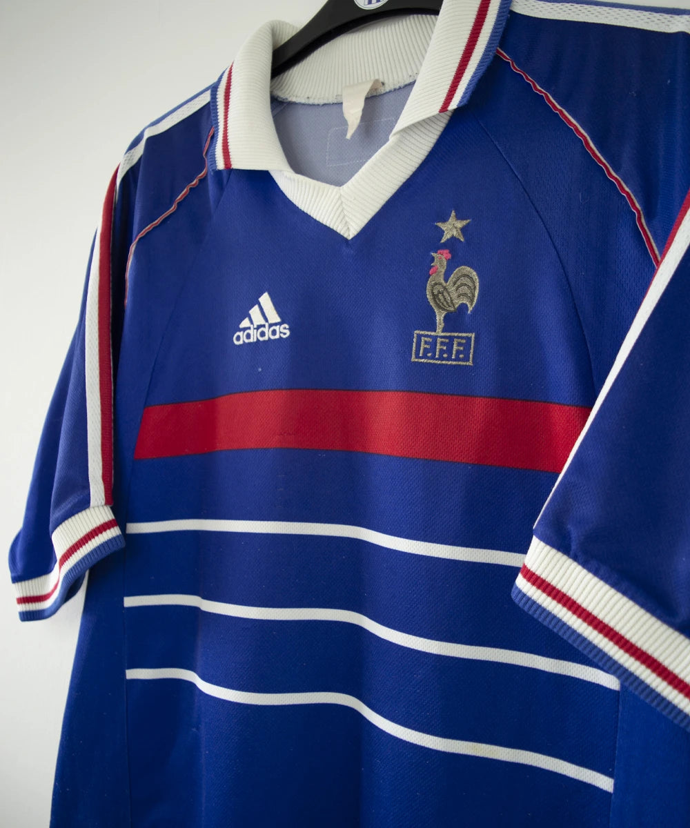 Maillot de foot vintage bleu blanc et rouge de l'équipe de france 1998. On peut retrouver l'équipementier adidas. Il s'agit d'un maillot authentique d'époque