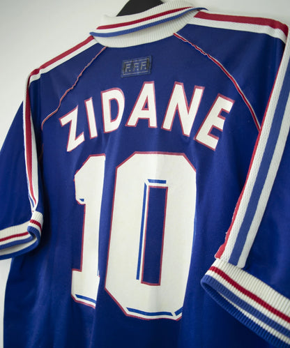 Maillot de foot vintage bleu blanc et rouge de l'équipe de france 1998. On peut retrouver l'équipementier adidas. Il s'agit d'un maillot authentique d'époque