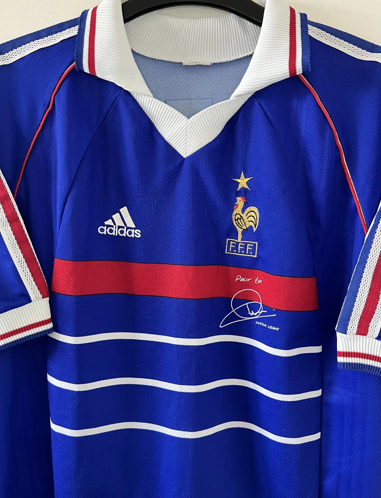 Maillot de foot vintage bleu blanc et rouge domicile de l'équipe de France 1998. On peut retrouver le sponsor adidas. On peut voir le coq avec l'étoile avec la signature "pour toi" de Zinedine Zidane. Il s'agit d'un maillot authentique.