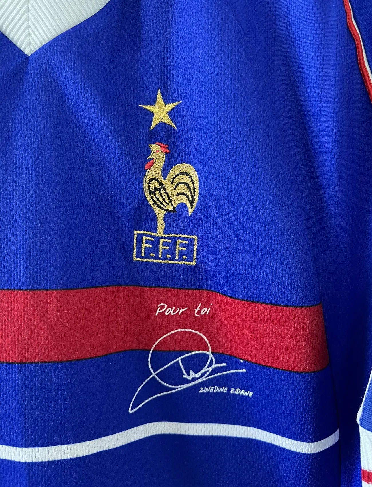 Maillot de foot vintage bleu blanc et rouge domicile de l'équipe de France 1998. On peut retrouver le sponsor adidas. On peut voir le coq avec l'étoile avec la signature "pour toi" de Zinedine Zidane. Il s'agit d'un maillot authentique.