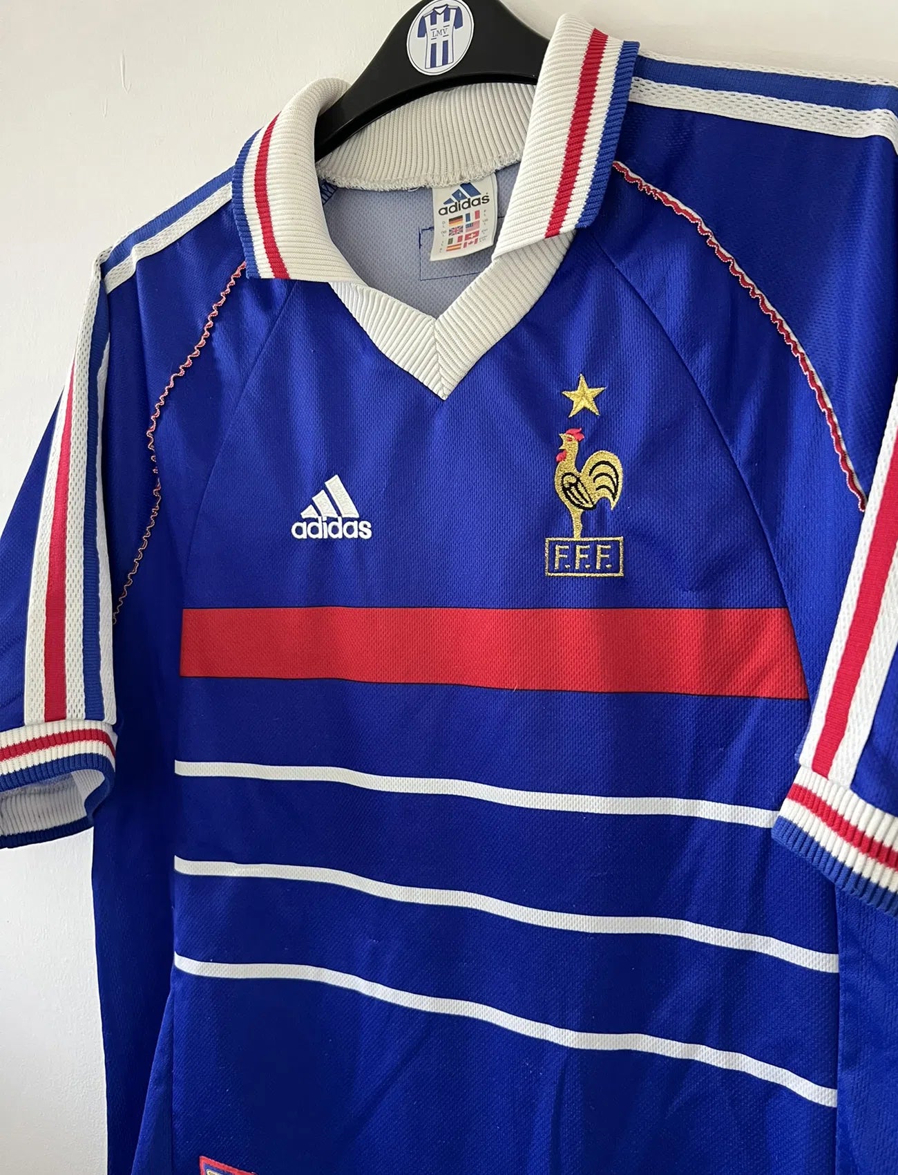 Maillot de foot vintage de l'équipe de france 98 bleu blanc et rouge. On peut retrouver l'équipementier adidas et le coq avec l'étoile. Il s'agit d'un maillot authentique édité lors de la coupe du monde 1998.