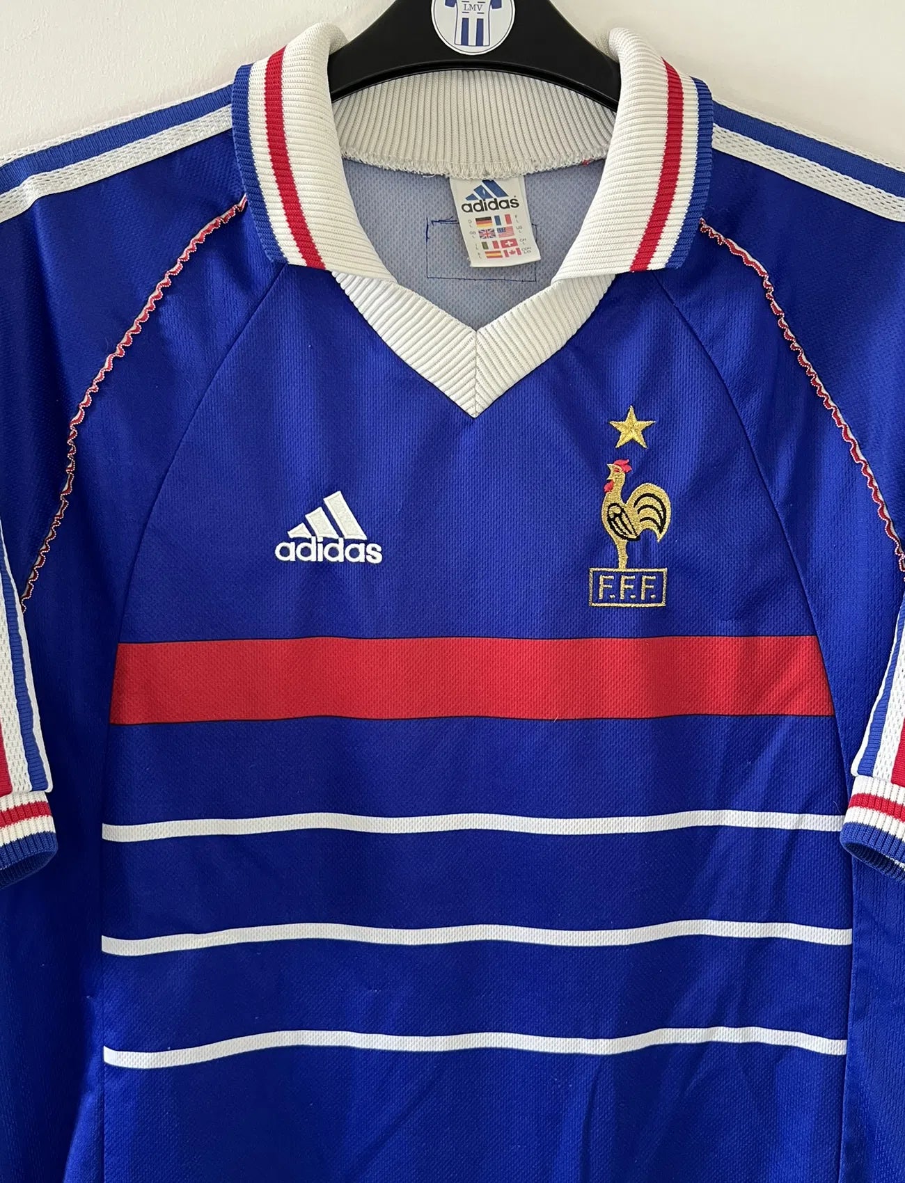 Maillot de foot vintage de l'équipe de france 98 bleu blanc et rouge. On peut retrouver l'équipementier adidas et le coq avec l'étoile. Il s'agit d'un maillot authentique édité lors de la coupe du monde 1998.