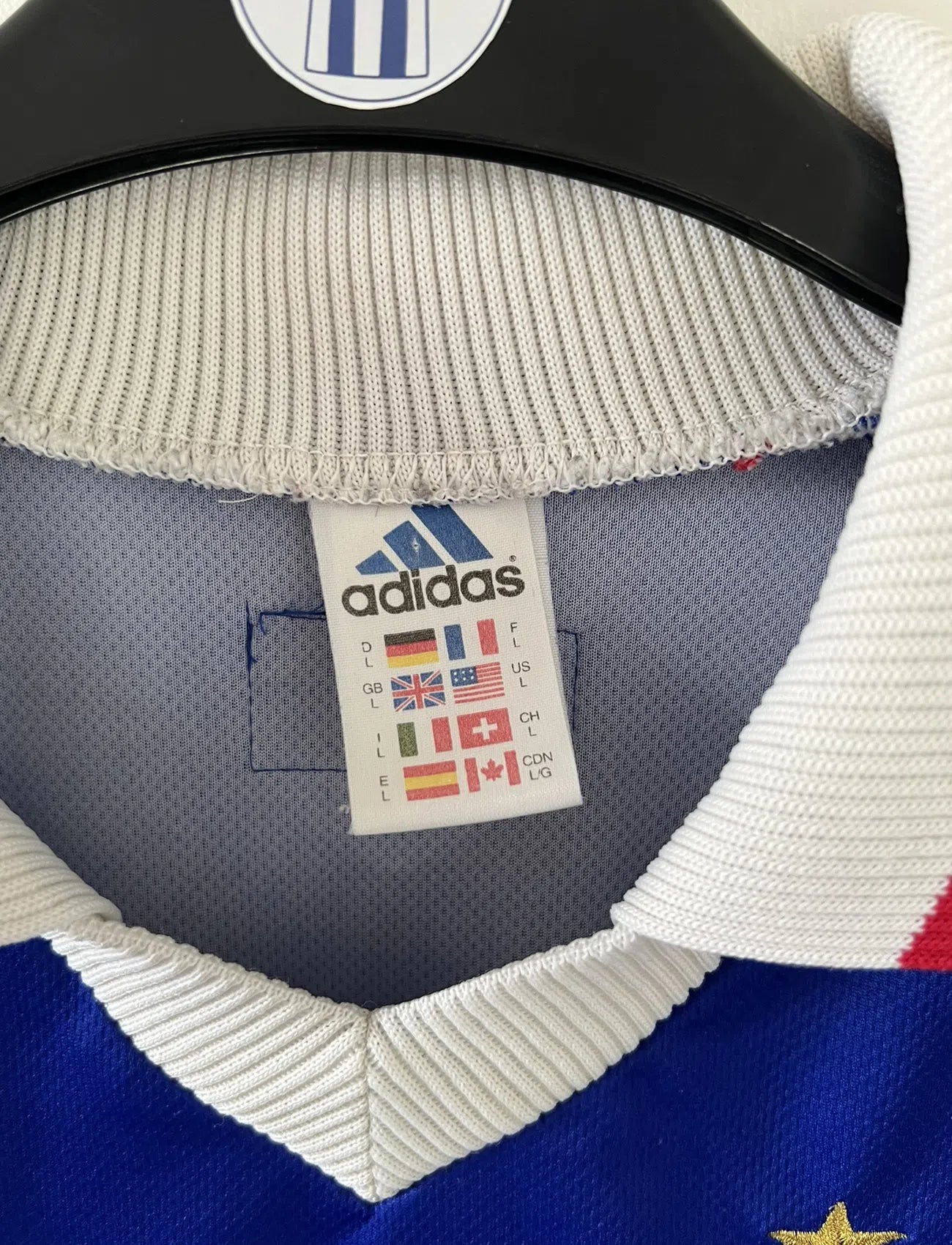 Maillot de foot vintage de l'équipe de france 98 bleu blanc et rouge. On peut retrouver l'équipementier adidas et le coq avec l'étoile. Il s'agit d'un maillot authentique édité lors de la coupe du monde 1998.