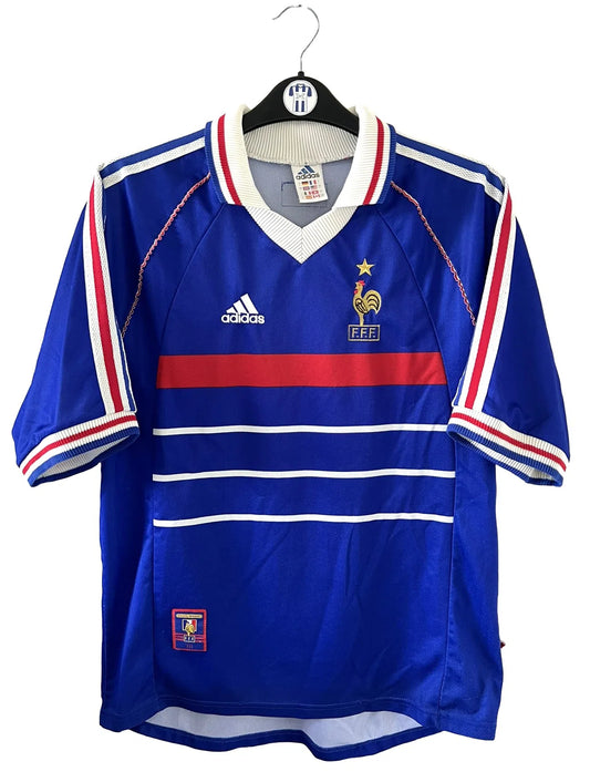 Maillot de foot vintage de l'équipe de france 98 bleu blanc et rouge. On peut retrouver l'équipementier adidas et le coq avec l'étoile. Il s'agit d'un maillot authentique édité lors de la coupe du monde 1998.