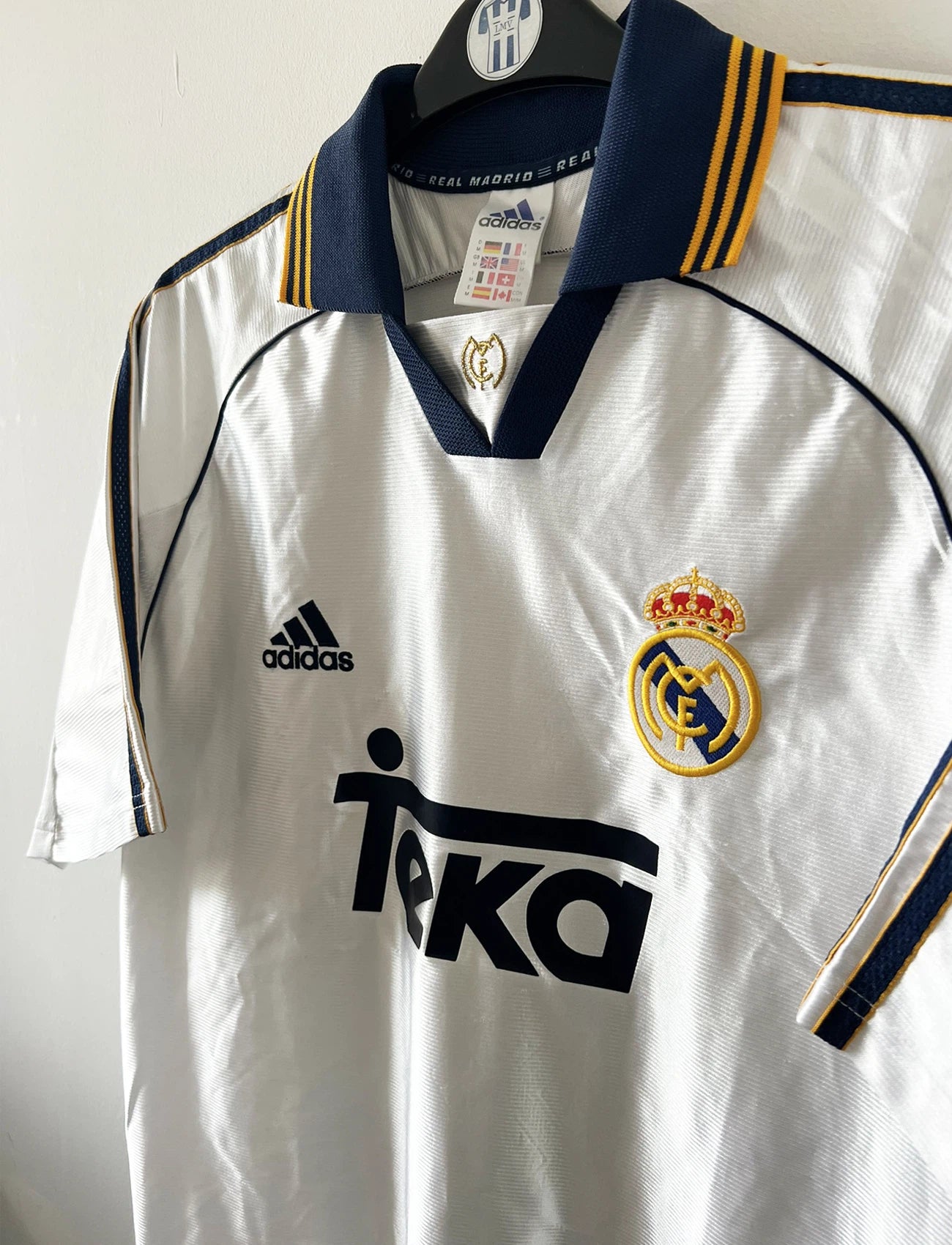 Sur cette photo on peut voir un maillot de foot vintage blanc du Real Madrid de la saison 1998 avec le sponsor Teka