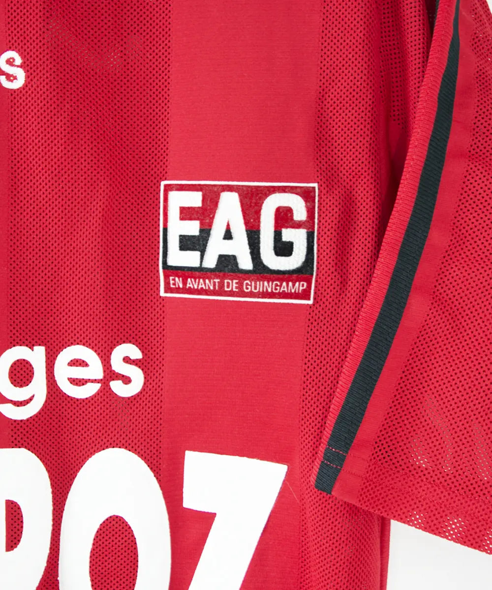 Maillot domicile rouge et noir de l'EA Guingamp de la saison 1996/1997. On peut retrouver le sponsor fromage rippoz et l'équipementier adidas