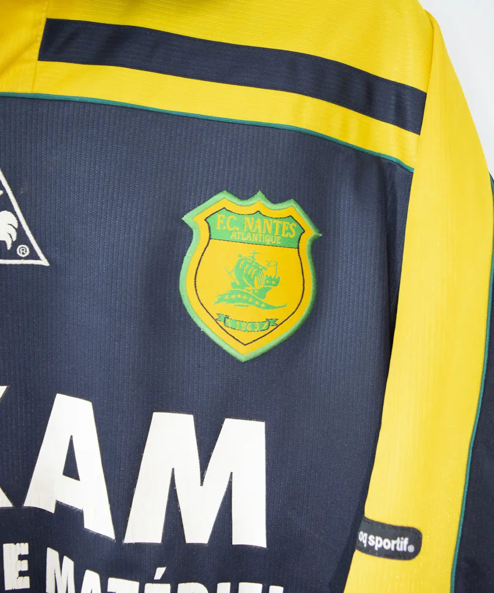 maillot de foot du fc nantes noir et jaune de la saison 2000-2001. On peut retrouver l"équipementier le coq sportif. On peut aussi retrouver à l'avant du maillot le sponsor loxam