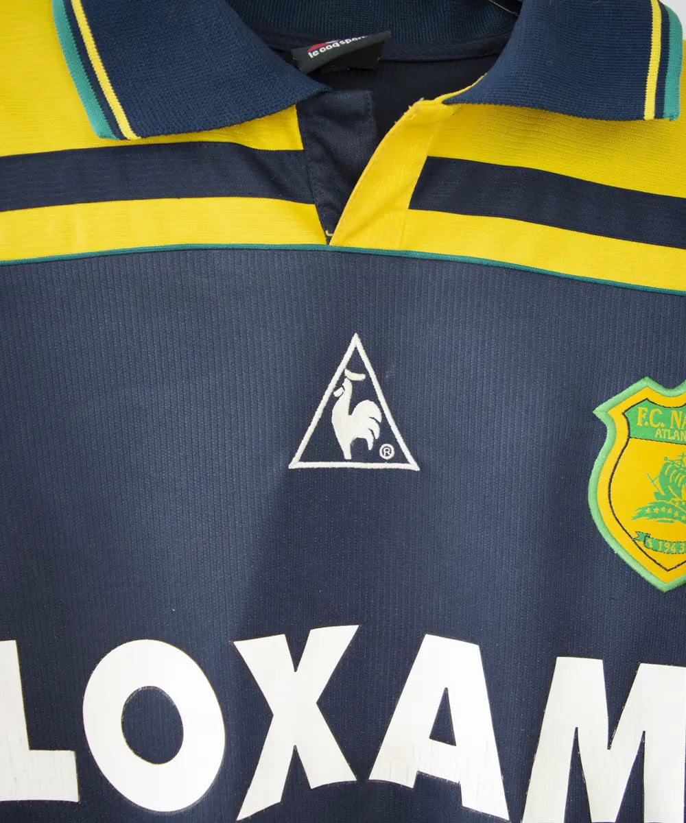 maillot de foot du fc nantes noir et jaune de la saison 2000-2001. On peut retrouver l"équipementier le coq sportif. On peut aussi retrouver à l'avant du maillot le sponsor loxam