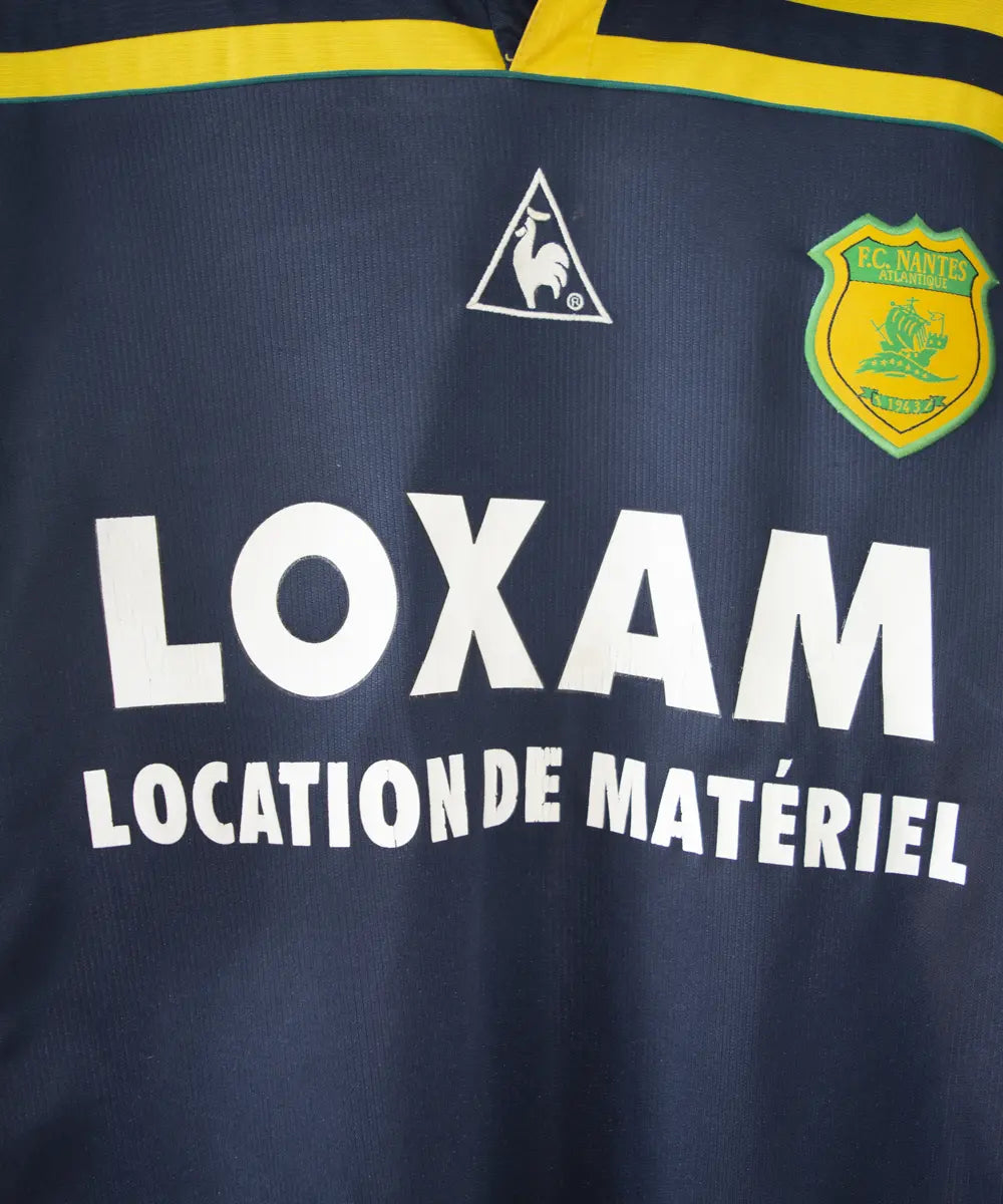 maillot de foot du fc nantes noir et jaune de la saison 2000-2001. On peut retrouver l"équipementier le coq sportif. On peut aussi retrouver à l'avant du maillot le sponsor loxam