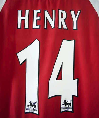 maillot authentique arsenal 2002-2004. Le maillot est de couleur rouge et blanche. On peut retrouver le sponsor O2 en feutrine et l'équipementier nike. Le maillot est floqué du numéro 14 Thierry Henry. Sur cette photo on peut voir le flocage de près