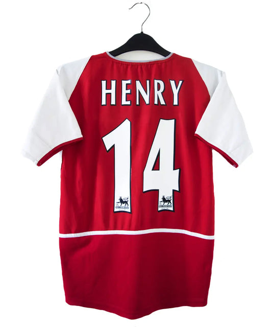 maillot authentique arsenal 2002-2004. Le maillot est de couleur rouge et blanche. On peut retrouver le sponsor O2 en feutrine et l'équipementier nike. Le maillot est floqué du numéro 14 Thierry Henry. Sur cette photo on peut voir le flocage