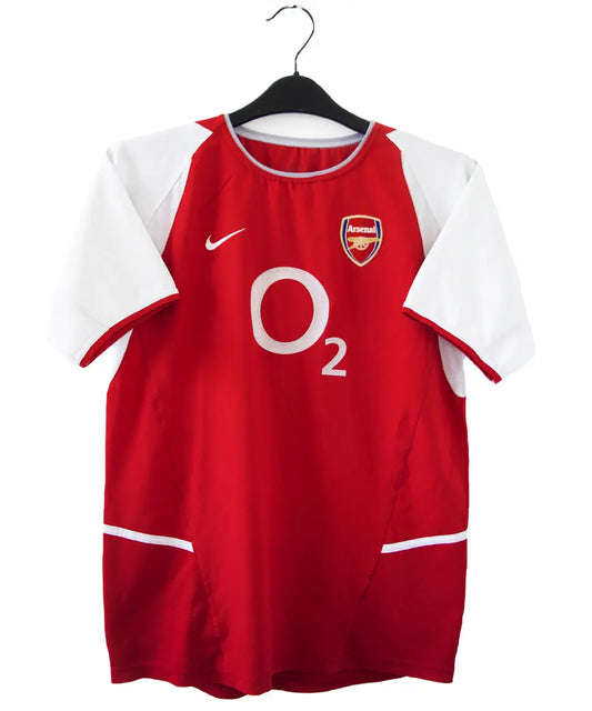 maillot authentique arsenal 2002-2004. Le maillot est de couleur rouge et blanche. On peut retrouver le sponsor O2 en feutrine et l'équipementier nike. Le maillot est floqué du numéro 14 Thierry Henry.