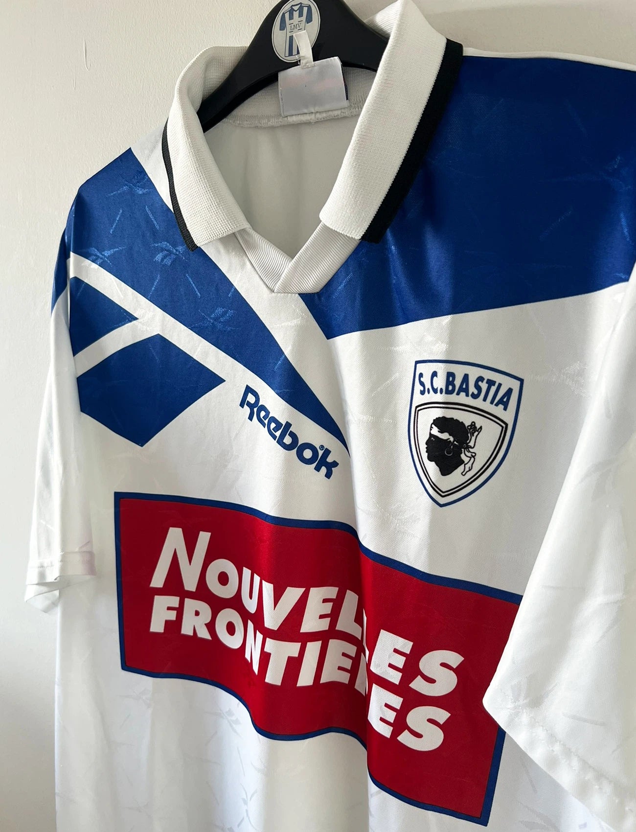 Maillot de foot vintage extérieur blanc du SC Bastia saison 1996/1997. On peut retrouver l'équipementier Reebok et le sponsor Nouvelles Frontières. Il s'agit d'un maillot authentique d'époque.