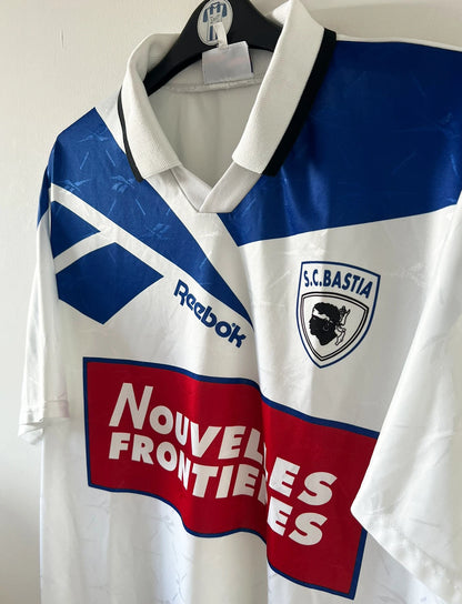 Maillot de foot vintage extérieur blanc du SC Bastia saison 1996/1997. On peut retrouver l'équipementier Reebok et le sponsor Nouvelles Frontières. Il s'agit d'un maillot authentique d'époque.