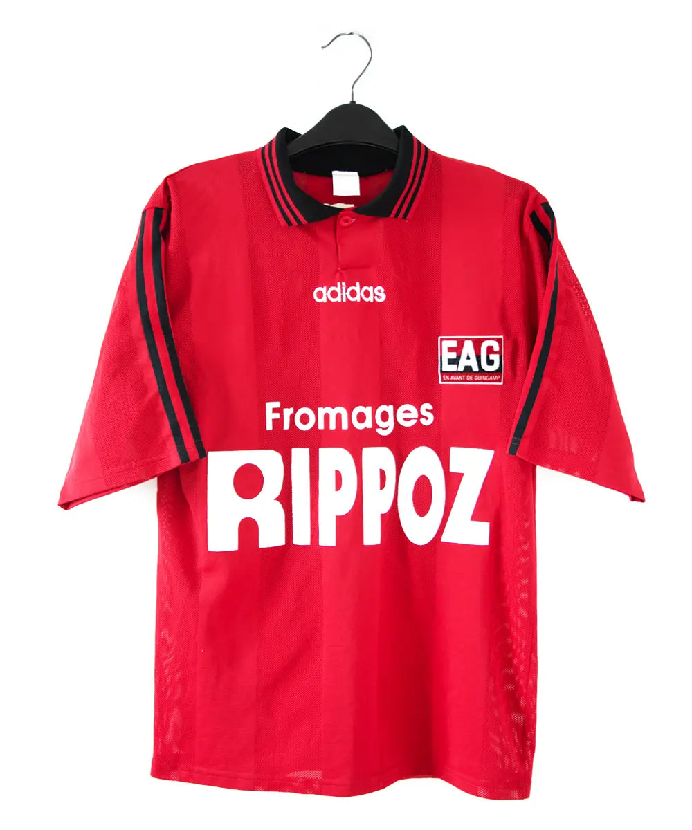 Maillot domicile rouge et noir de l'EA Guingamp de la saison 1996/1997. On peut retrouver le sponsor fromage rippoz et l'équipementier adidas