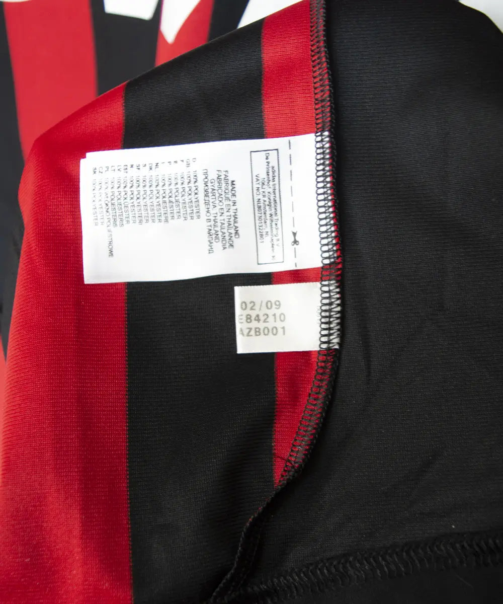 Maillot domicile noir et rouge de l'ac milan de la saison 2009-2010. On peut retrouver l'équipementier adidas et le sponsor bwin. Sur cette photo on peut voir l'étiquette d'authenticité comportant les numéros E84210