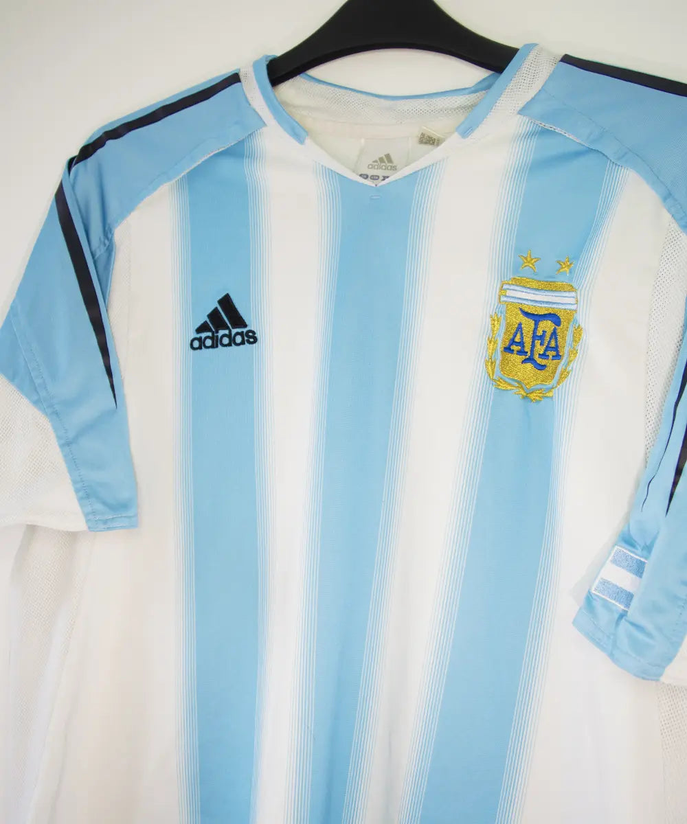 Maillot de foot authentique de l'argentine de la saison 2004-2005. Le maillot est de couleur bleu ciel et blanc. On peut retrouver l'équipementier adidas. Sur cette photo on peut voir le maillot de côté
