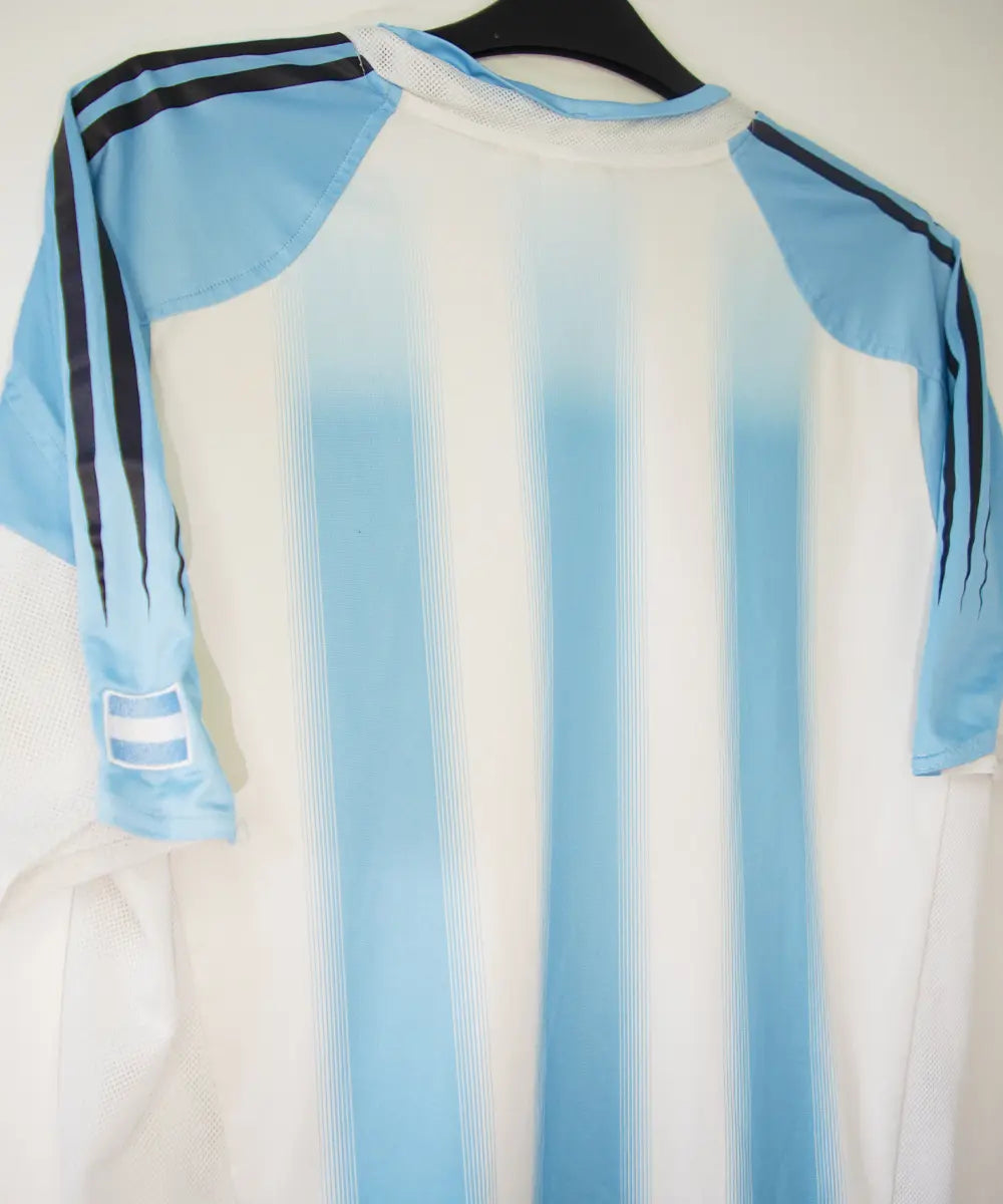 Maillot de foot authentique de l'argentine de la saison 2004-2005. Le maillot est de couleur bleu ciel et blanc. On peut retrouver l'équipementier adidas. Sur cette photo on peut voir le maillot de dos de côté