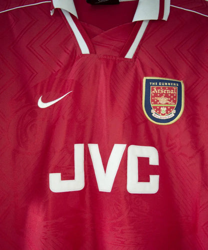 Maillot domicile d'arsenal de la saison 1996-1997 de couleur rouge et blanc. On peut retrouver l'équipementier nike et le sponsor JVC.