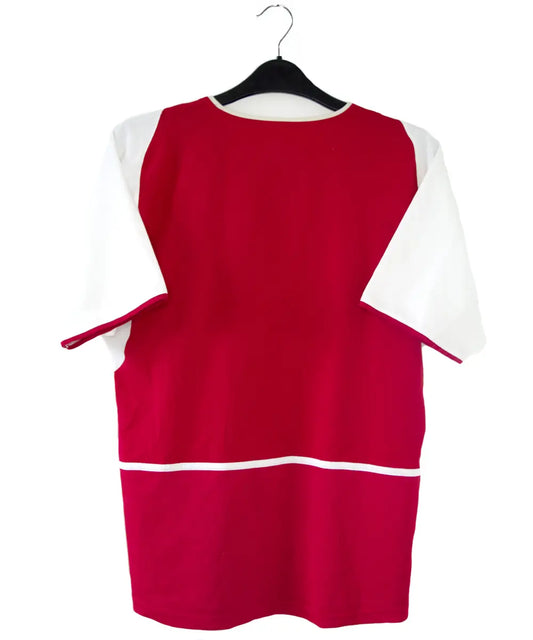 Maillot domicile Arsenal rouge et blanc de la saison 2002-2004. On peut retrouver l'équipementier nike et le sponsor O2.