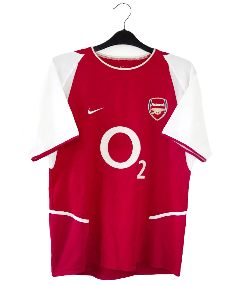 Maillot domicile Arsenal rouge et blanc de la saison 2002-2004. On peut retrouver l'équipementier nike et le sponsor O2. 