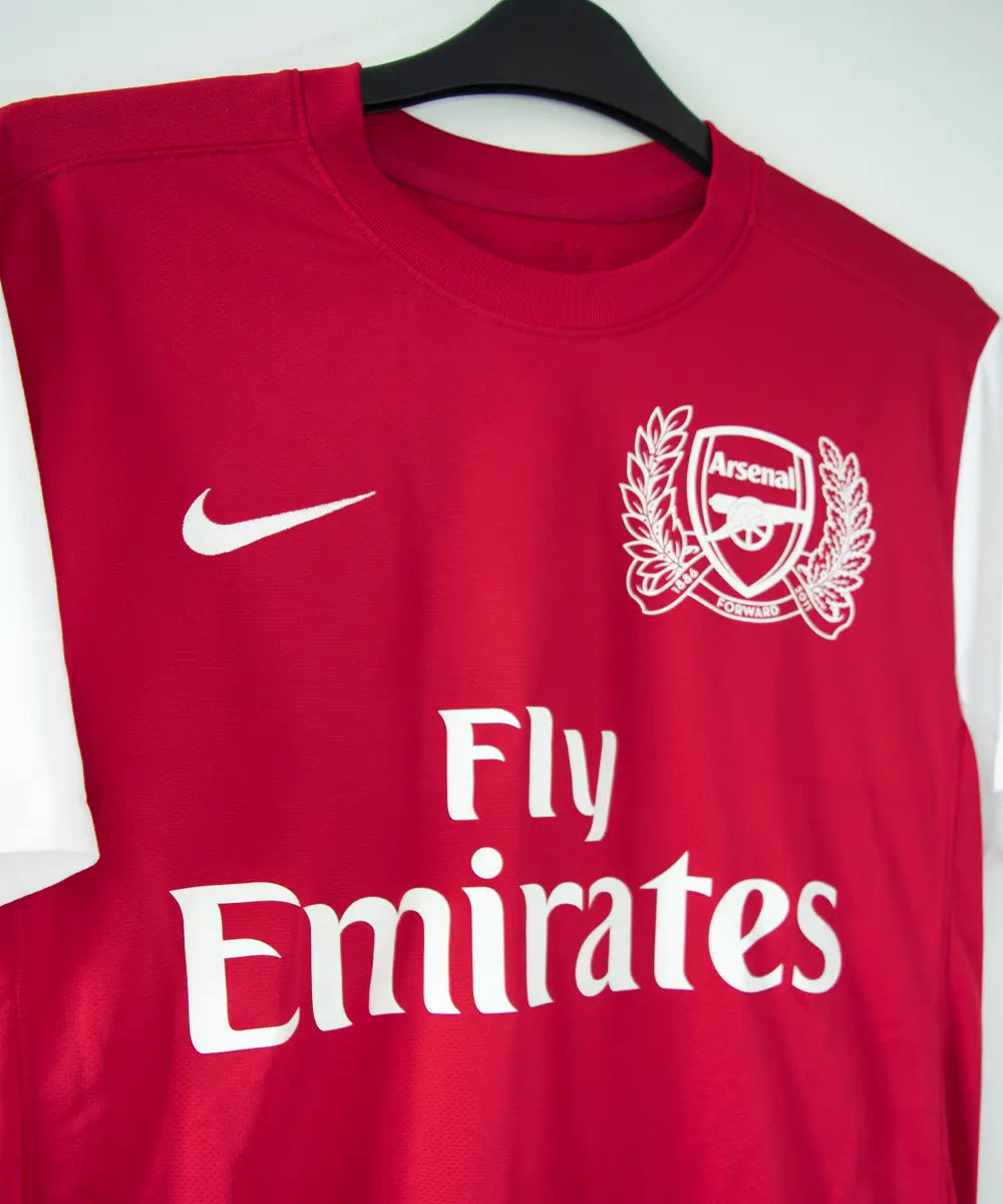 Maillot domicile d'Arsenal de la saison 2011-2012. On peut retrouver l'équipementier nike et le sponsor fly emirates. Le maillot est floqué du numéro 12 Thierry Henry